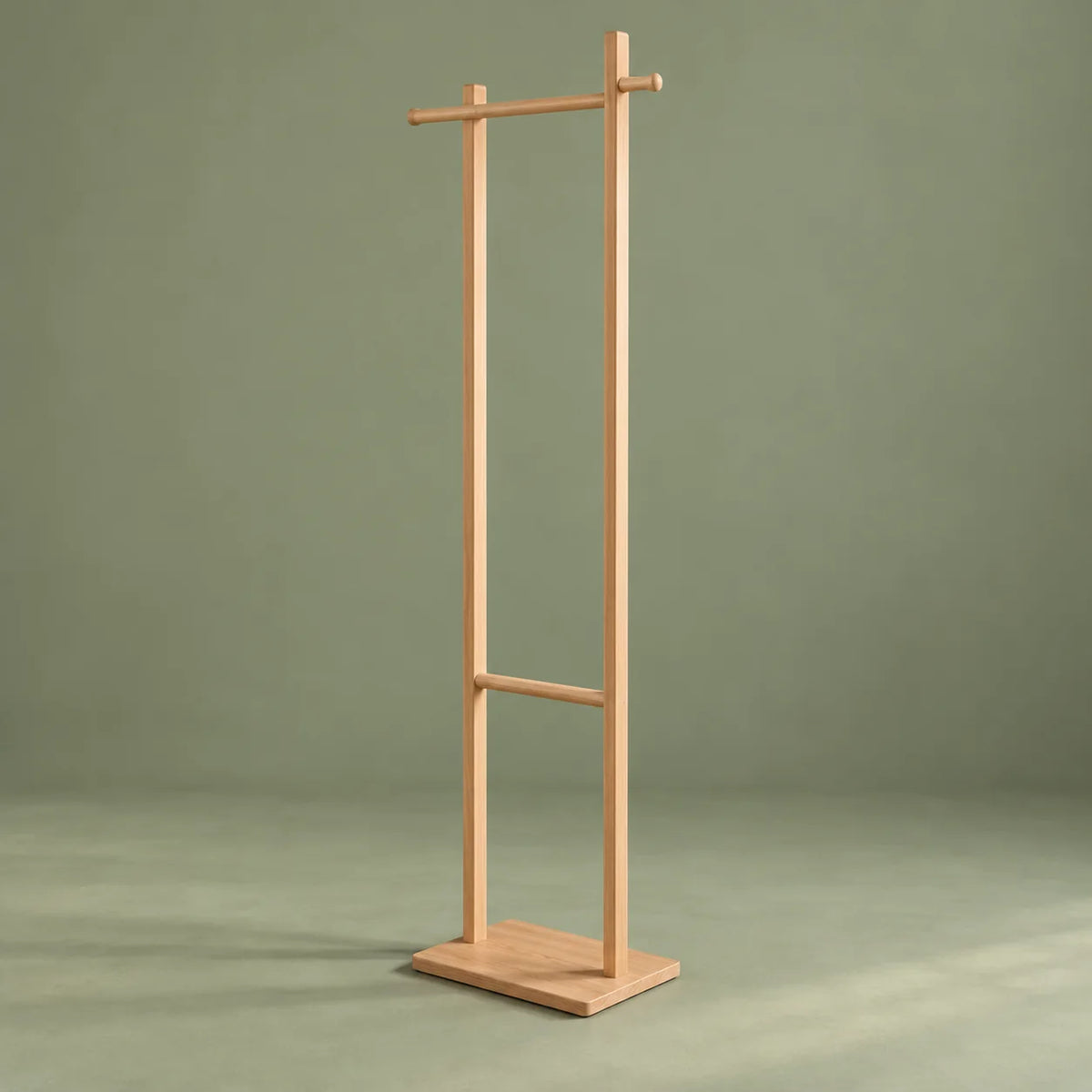 Vue entière de trois quarts du porte-manteau sur pied en bois clair sur fond vert sauge