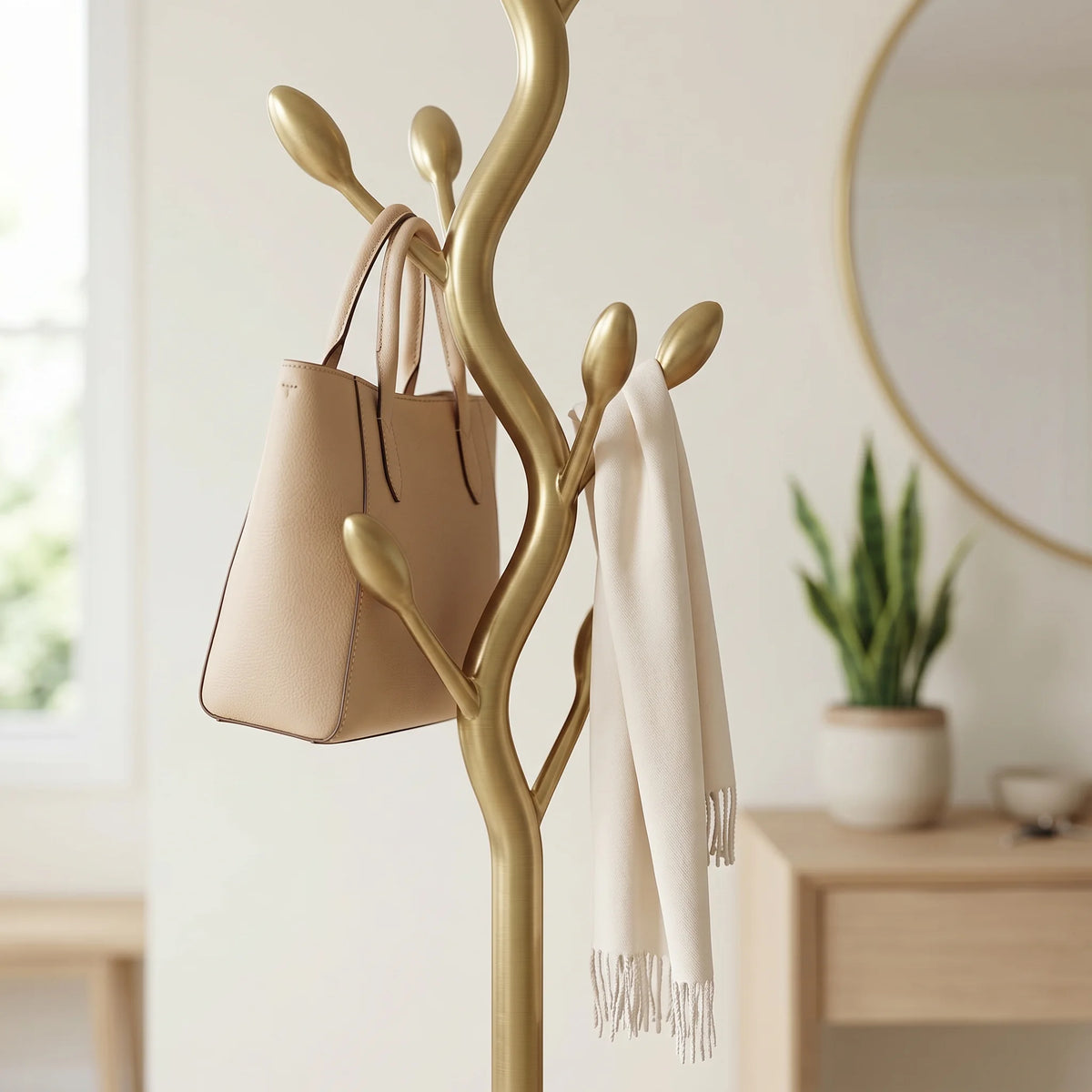 Gros plan sur les branches dorées à embouts en bouton, le sac beige et l’écharpe ivoire du porte-manteau dans une entrée