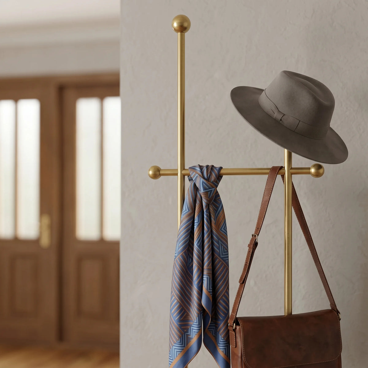 Gros plan sur la traverse dorée à embouts ronds, le chapeau gris, le foulard bleu et orange et le sac en cuir brun