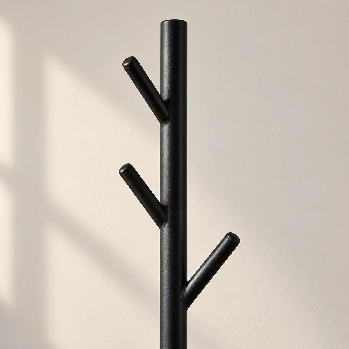 Gros plan des patères inclinées noires du porte-manteau arbre