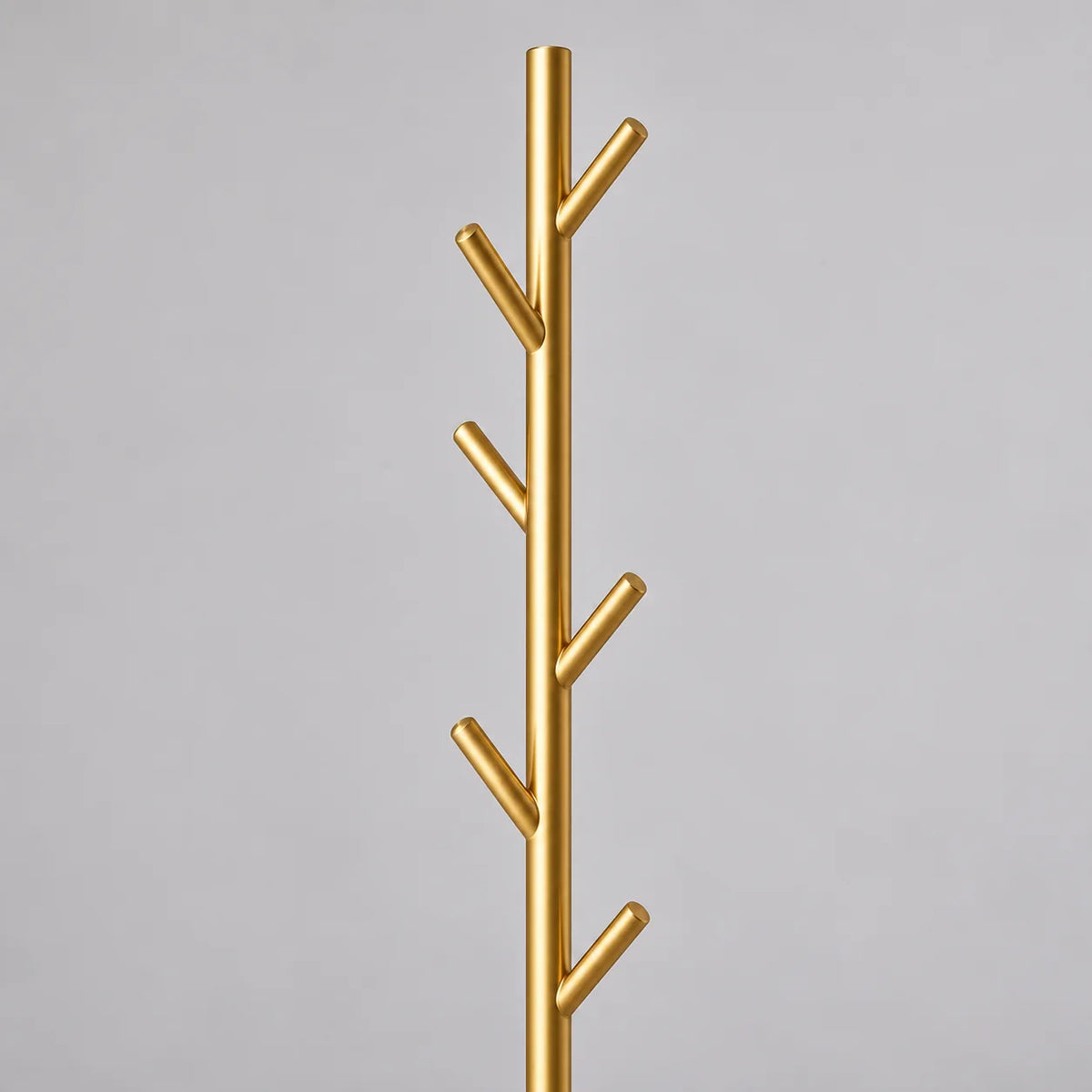 Gros plan des patères en branches dorées du porte-manteau arbre
