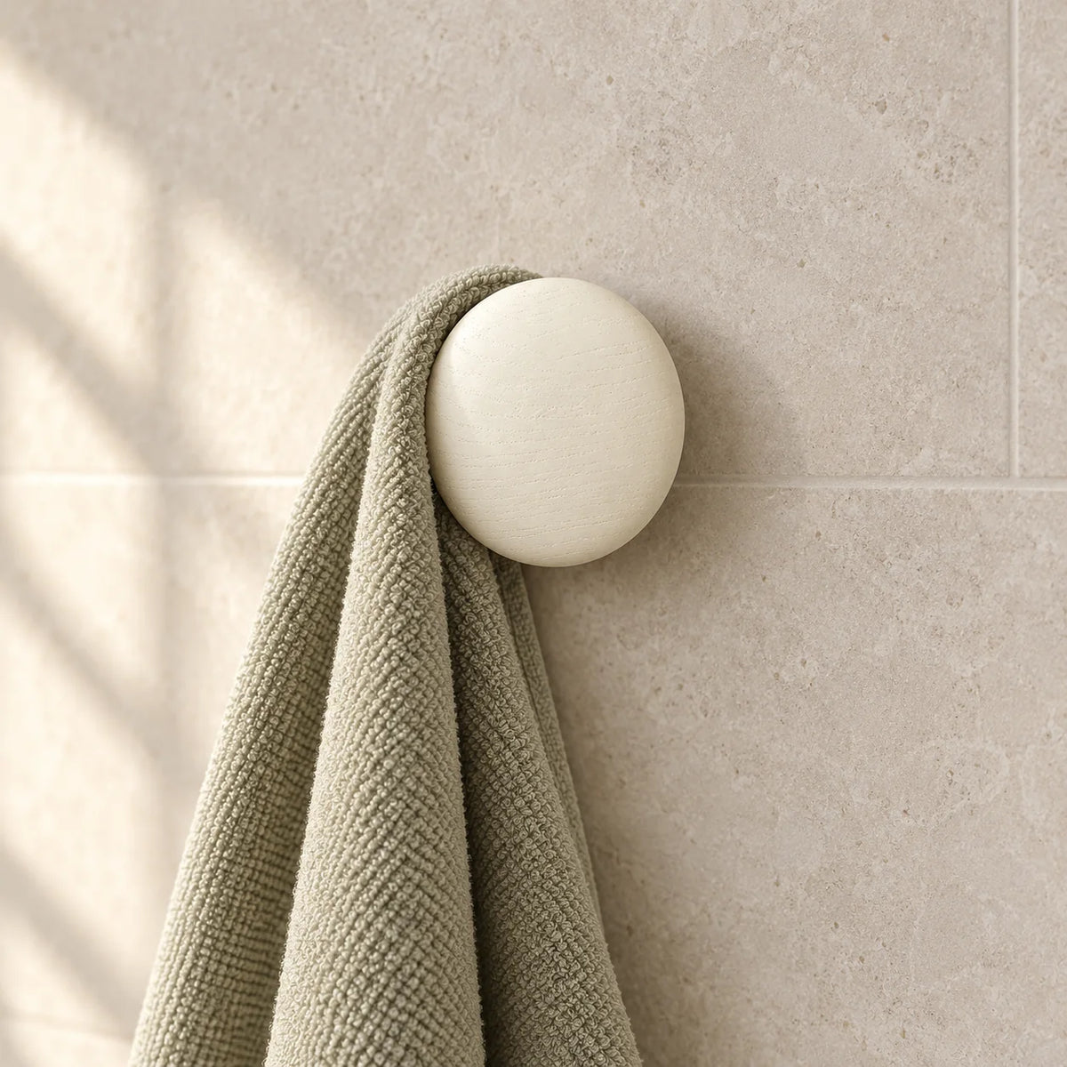 Patère ronde blanche portant une serviette en salle de bain