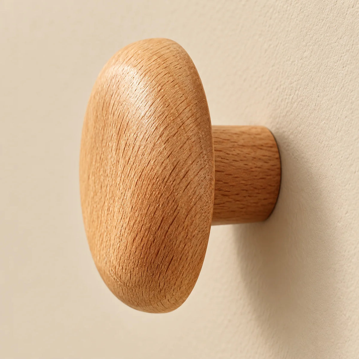 Vue de profil de la patère ronde montrant sa fixation cylindrique en bois