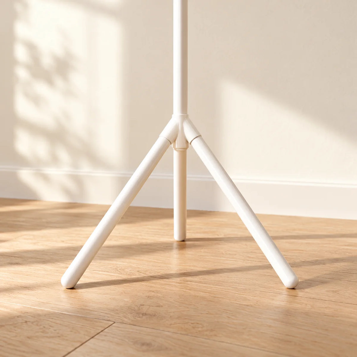 Détail de la base à trois pieds du porte-manteau blanc sur parquet