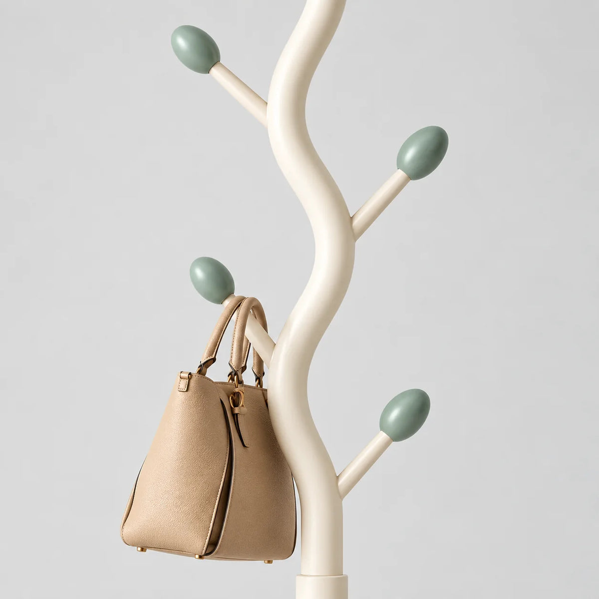 Détail des branches ivoire à embouts ovales vert sauge et du sac beige suspendu sur fond gris
