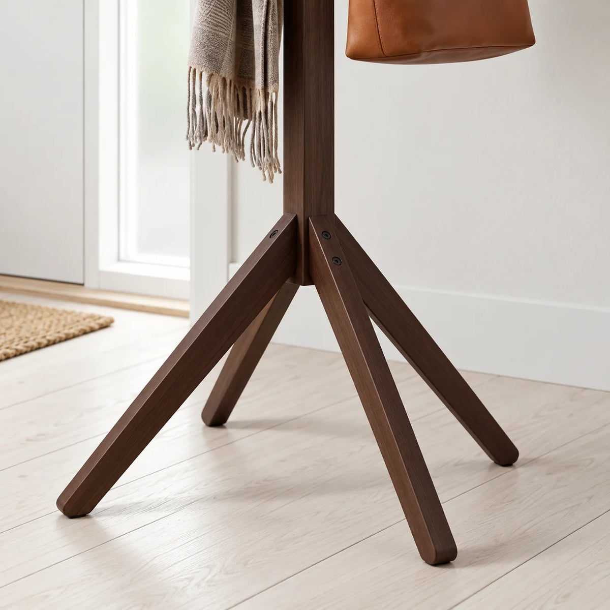 Détail des quatre pieds évasés du porte-manteau arbre en bois foncé