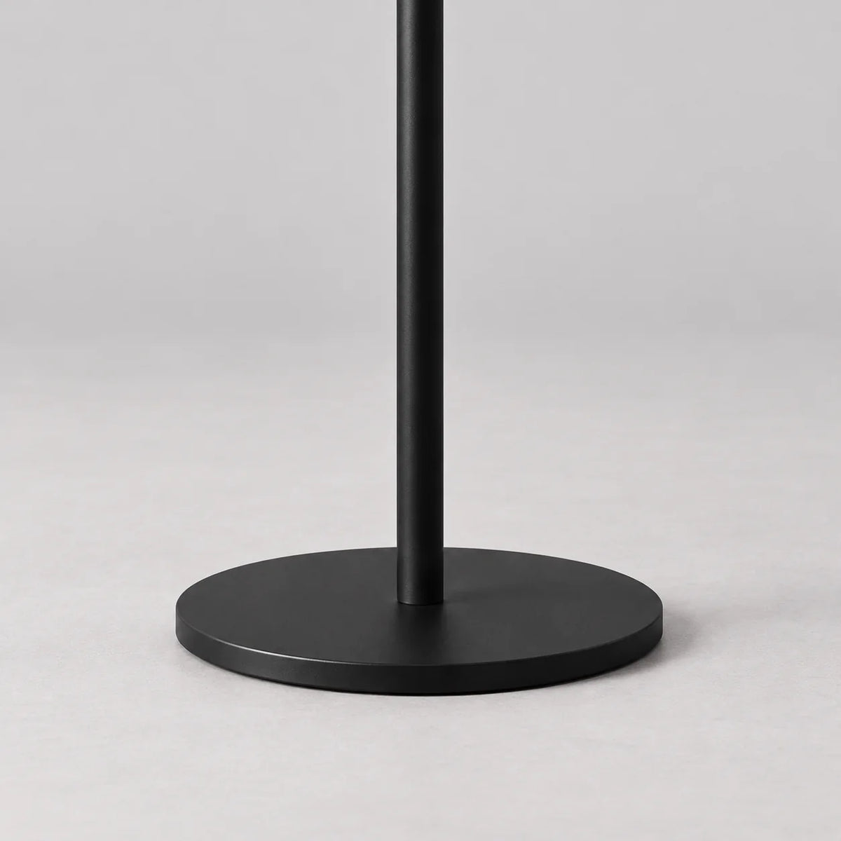 Gros plan de la base ronde noire et du pied noir du porte-manteau champignon