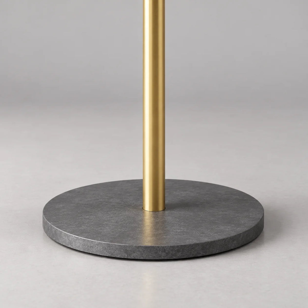 Détail de la base circulaire gris anthracite et de la tige dorée du porte-manteau