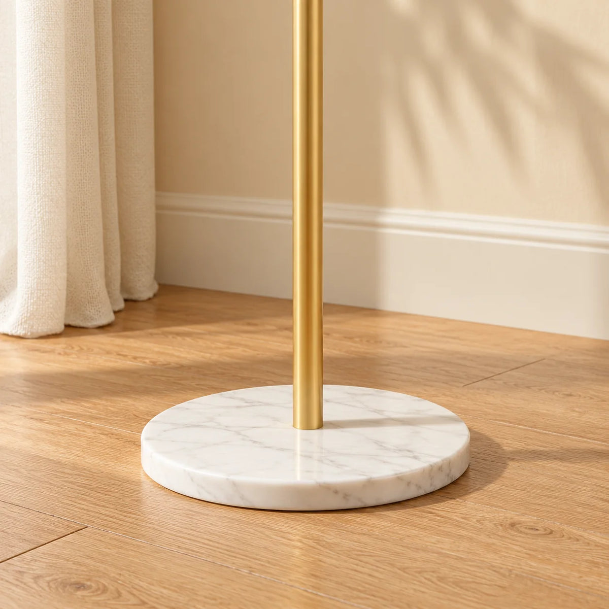 Détail du pied doré et du socle rond blanc du porte-manteau Nuage d'or