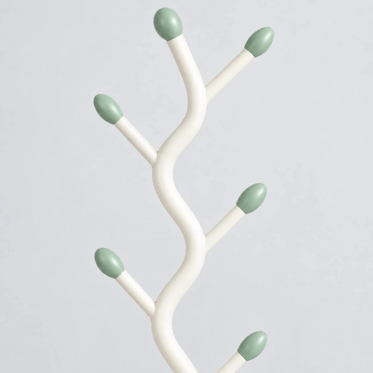 Détail des branches blanches et embouts vert sauge du porte-manteau sur pied