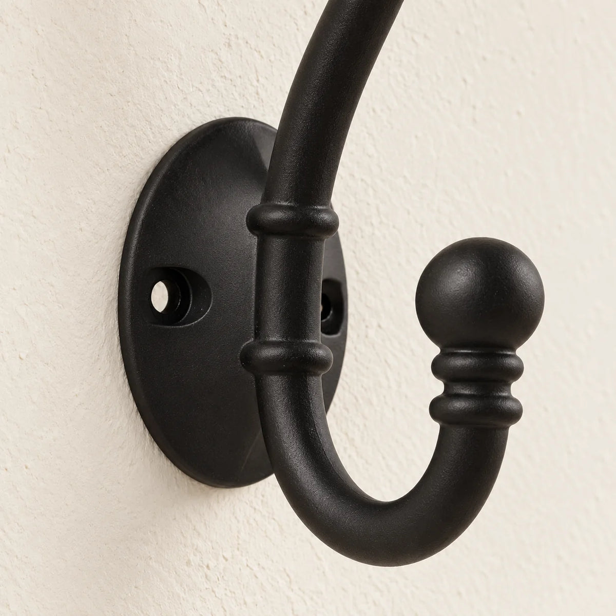 Gros plan de la plaque de fixation ovale et du crochet inférieur de la patère noire