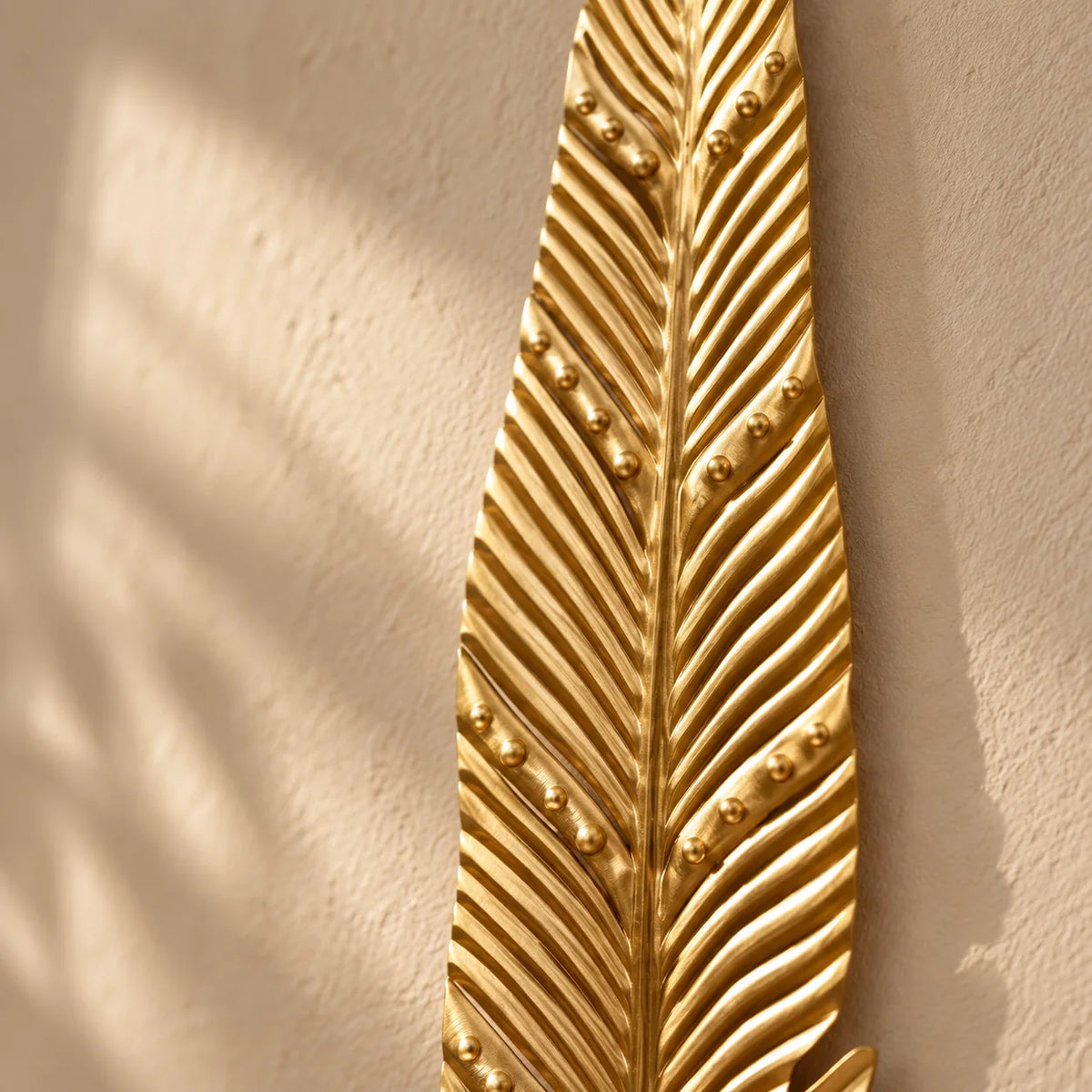 Détail des nervures en métal doré de la patère longue feuille