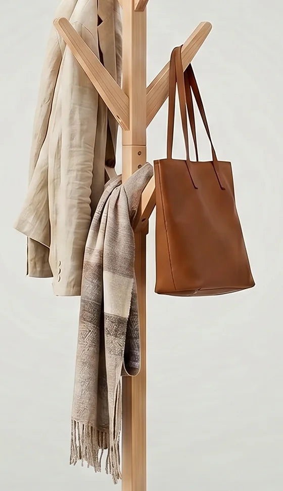 Détail des crochets en bois clair portant un sac cognac et une écharpe beige