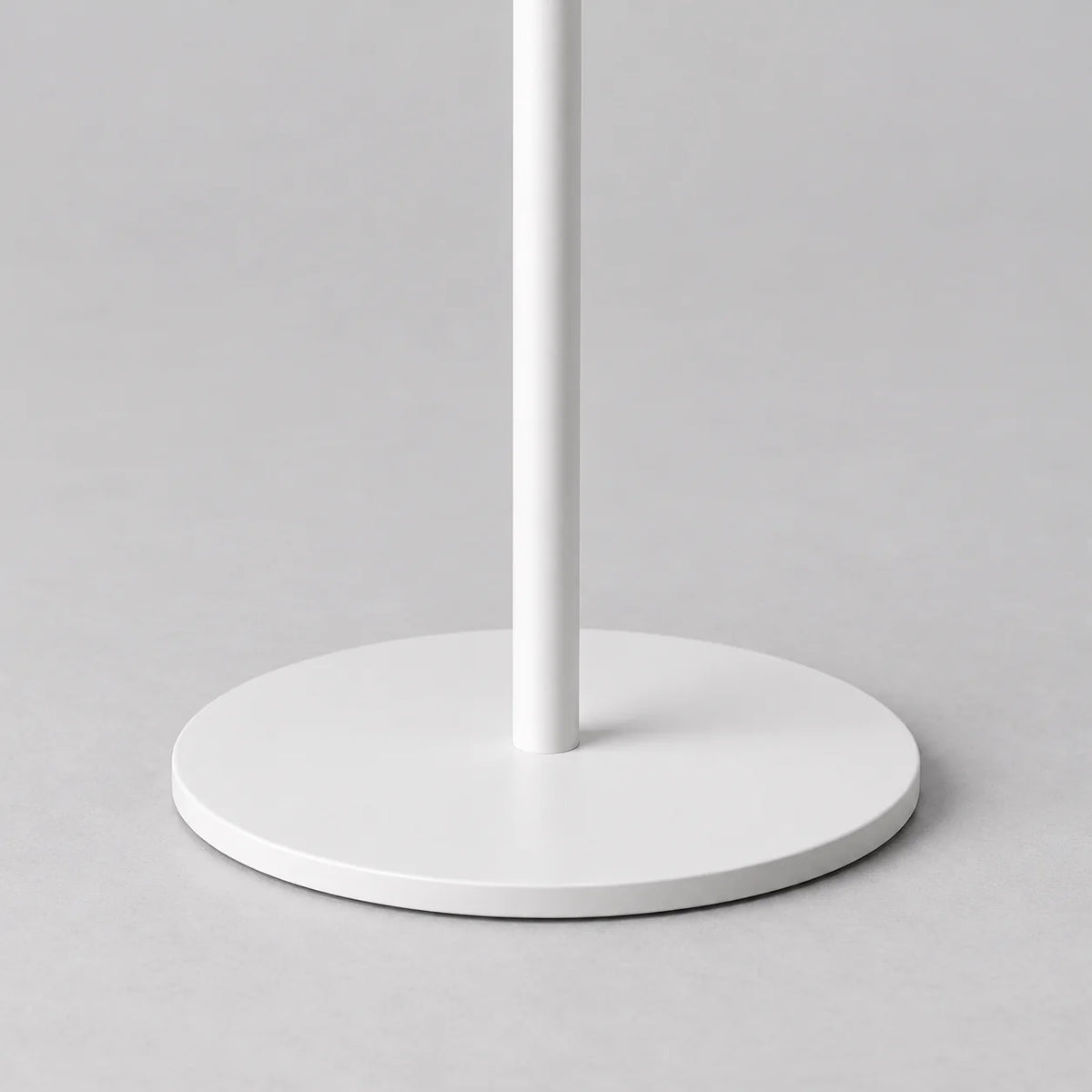 Gros plan du pied et de la base circulaire blanche du porte-manteau arbre