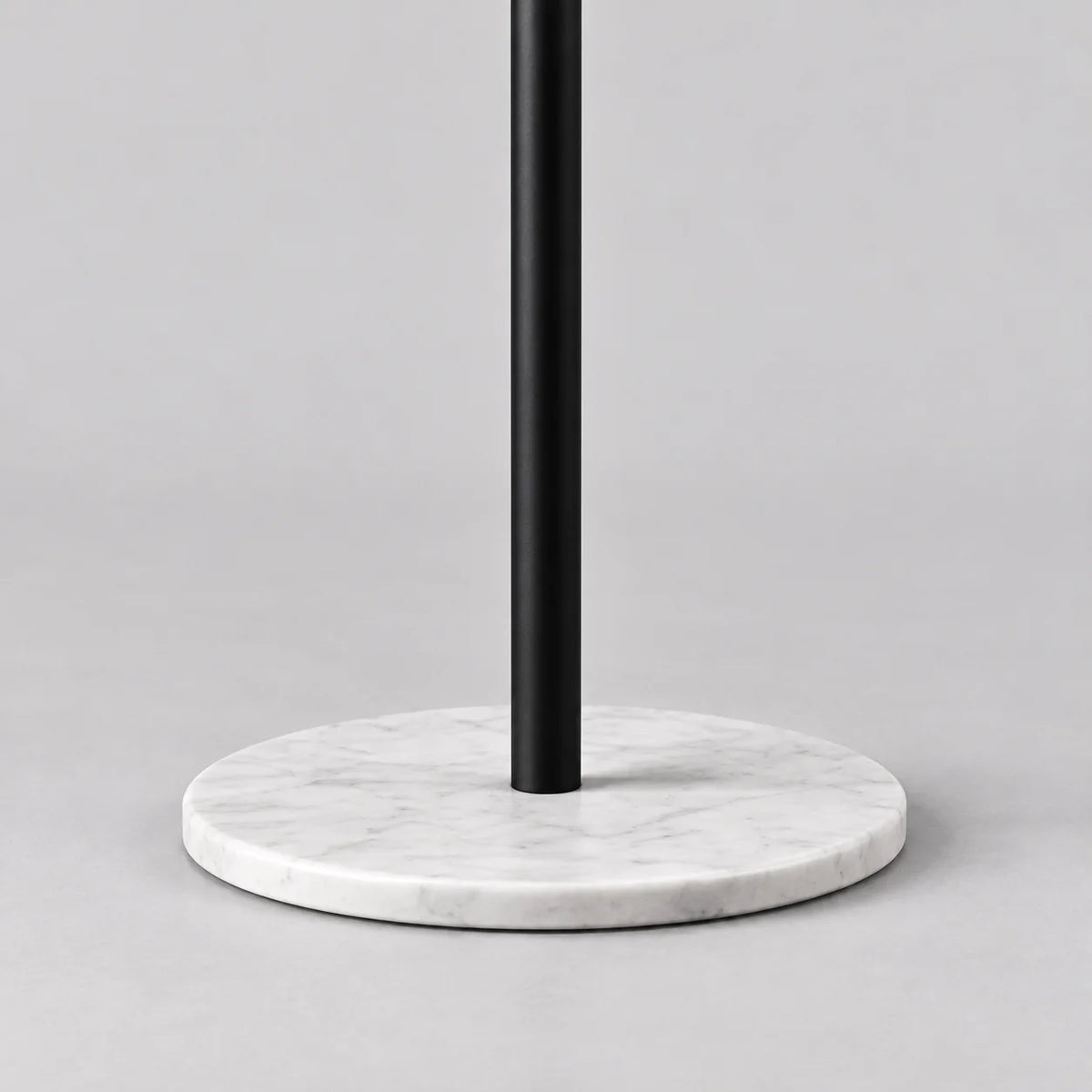 Gros plan de la base ronde en marbre blanc et du pied noir du porte-manteau