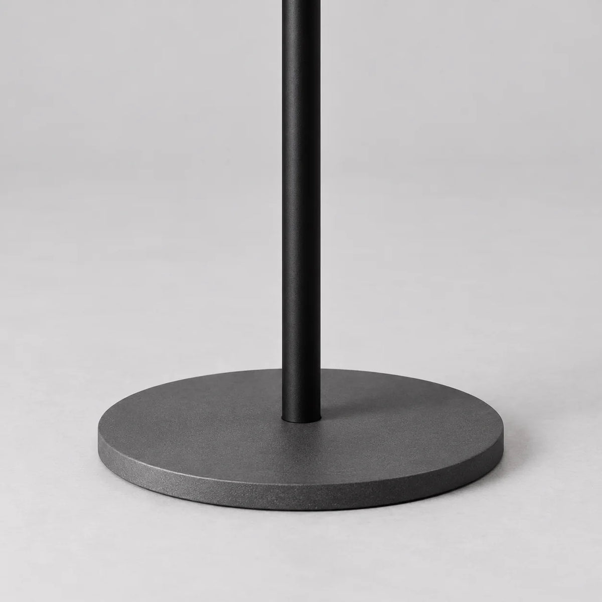Gros plan de la base ronde gris anthracite et du pied noir du porte-manteau