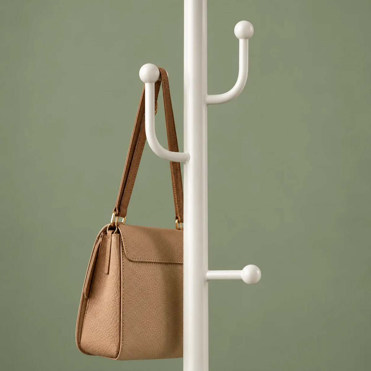 Détail des crochets médians blancs portant un sac beige sur fond vert sauge