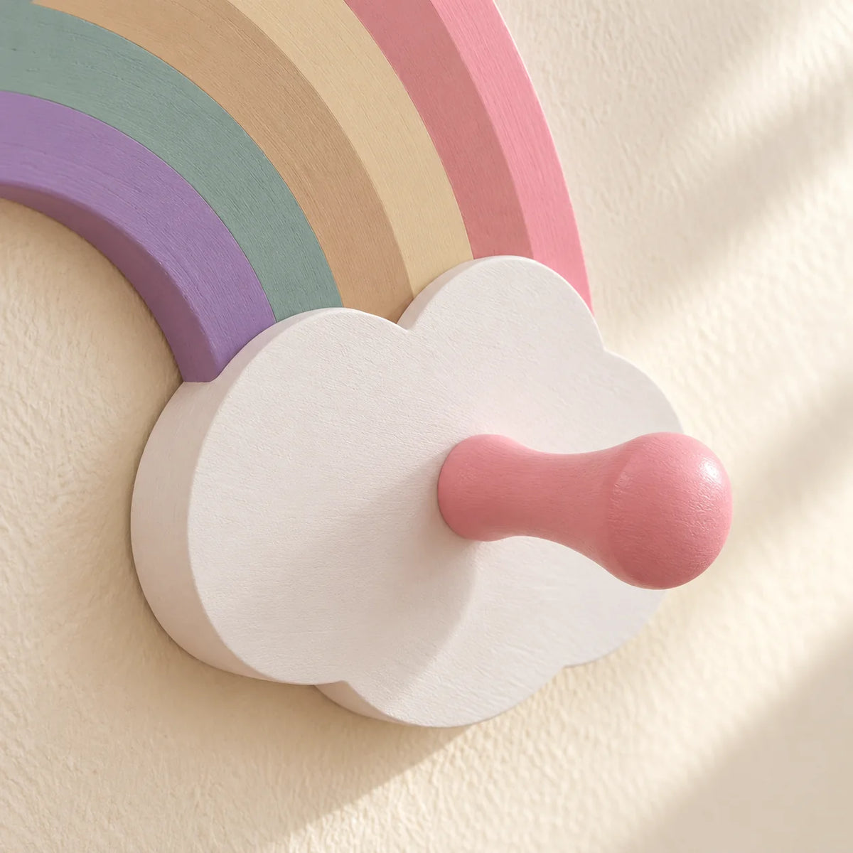 Gros plan du nuage blanc, du crochet rose et des bandes colorées du porte-manteau enfant