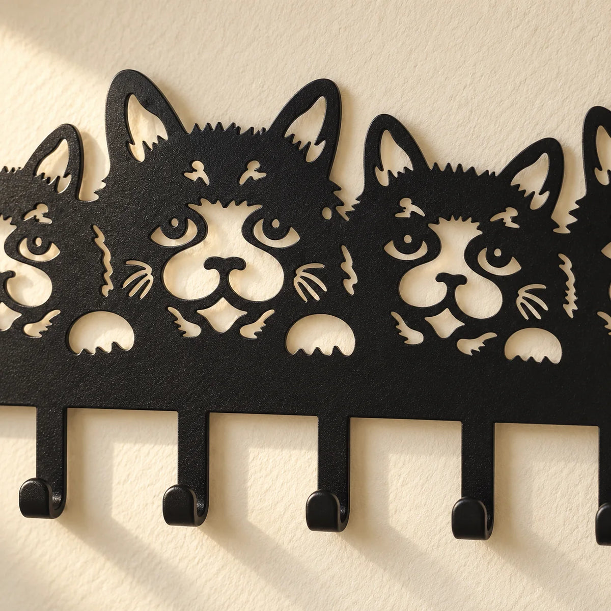 Gros plan des visages de chats découpés dans le métal noir et des crochets