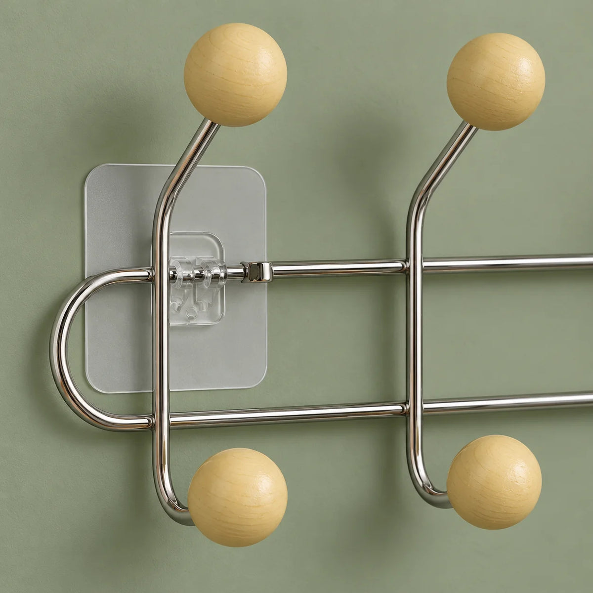 Gros plan des boules bois jaune crème, tubes chromés et fixation transparente sur fond vert
