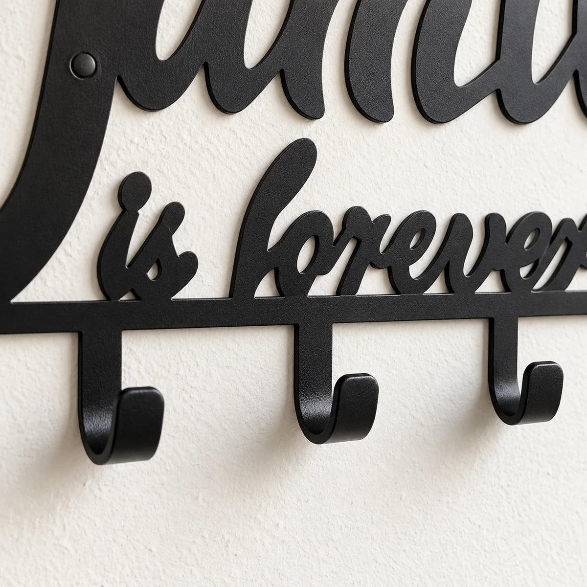 Gros plan du lettrage is forever et des crochets en fer noir du porte-manteau Family