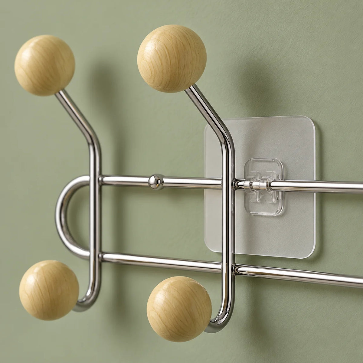 Gros plan des boules bois jaune crème, tubes chromés et fixation transparente sur fond vert