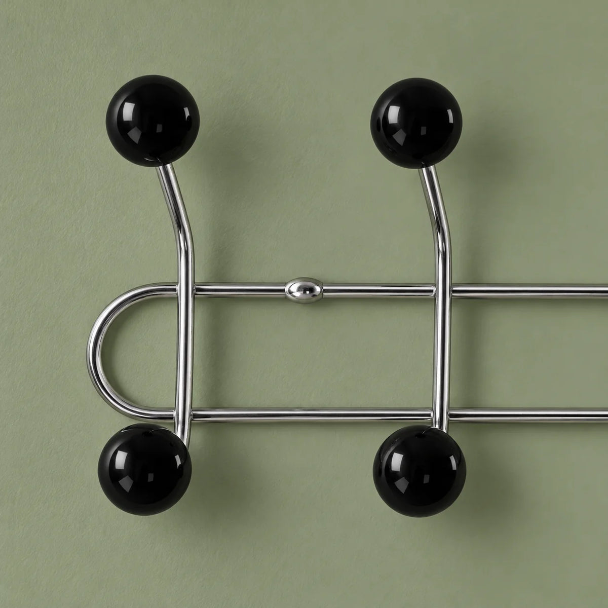 Gros plan des boules noires brillantes et tubes chromés sur fond vert sauge
