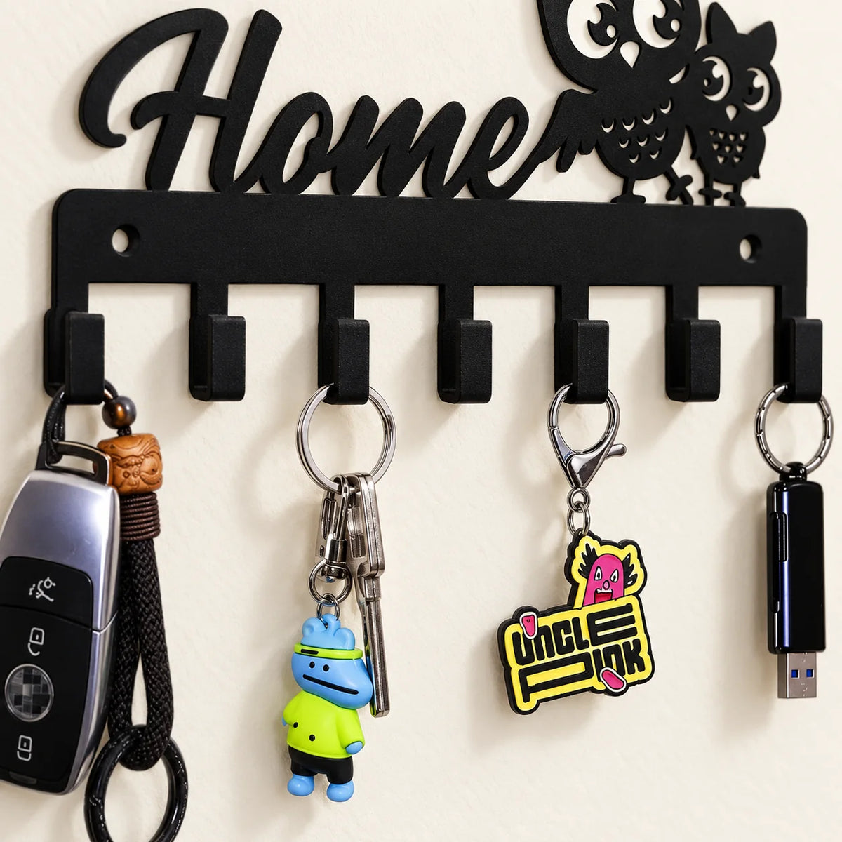 Gros plan sur les sept crochets en fer noir et des clés suspendues au porte-clés Home