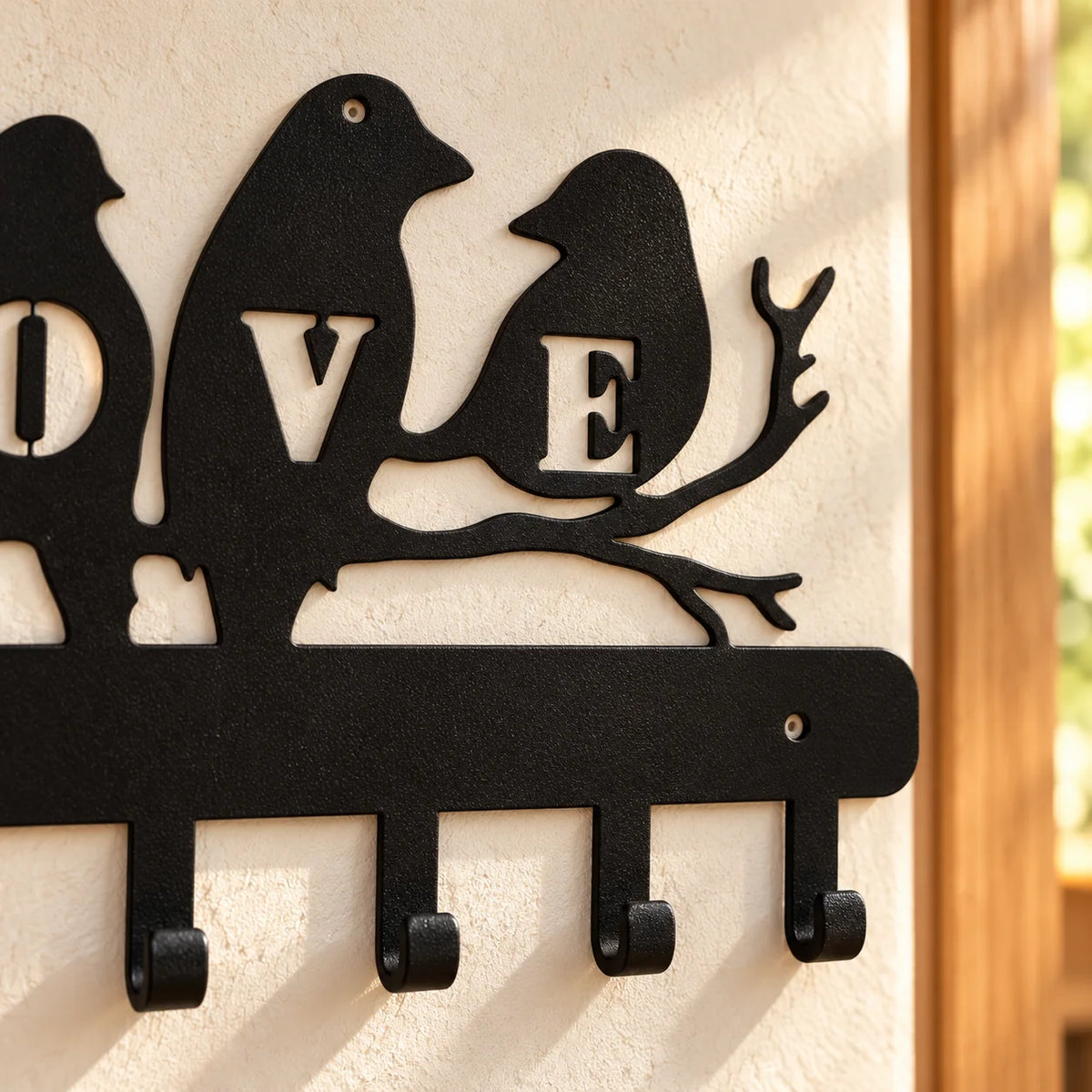 Gros plan du métal noir, des oiseaux, branches et crochets du porte-manteau LOVE