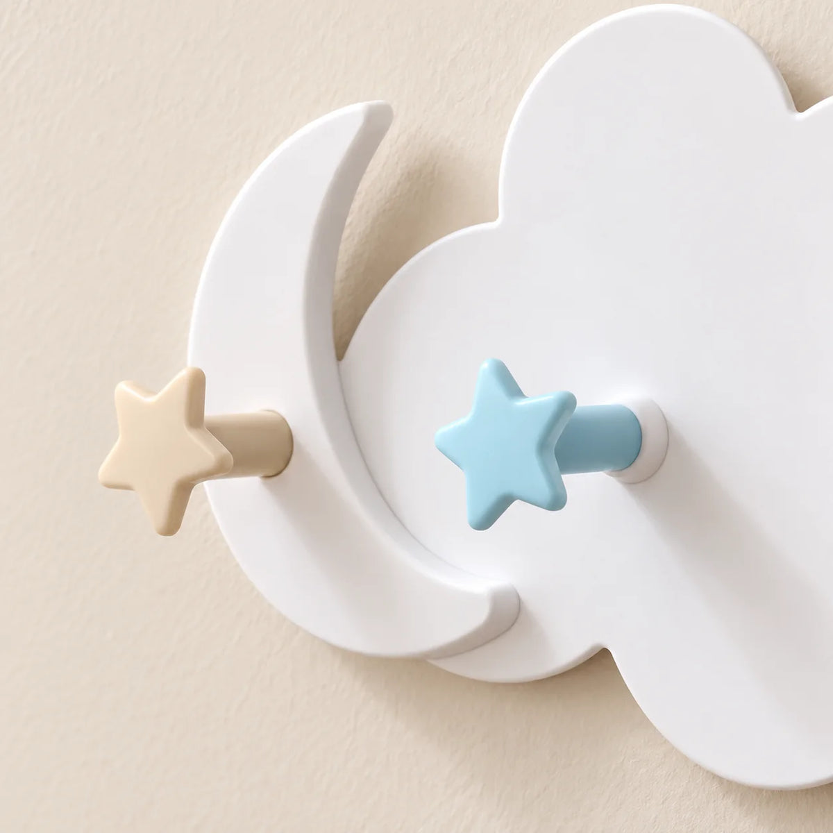 Gros plan du croissant de lune et des patères étoile beige et bleue du porte-manteau Nuage