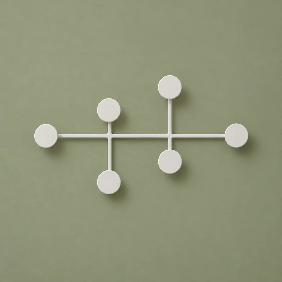 Porte-manteau mural blanc à six pastilles, vue de face sur fond vert sauge
