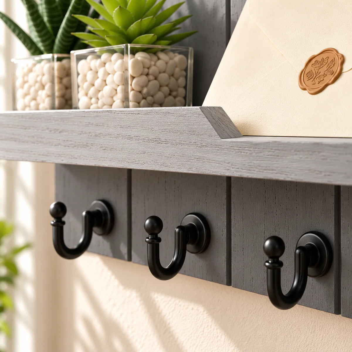 Gros plan du rebord de la tablette en bois gris clair et des crochets noirs dans l’entrée