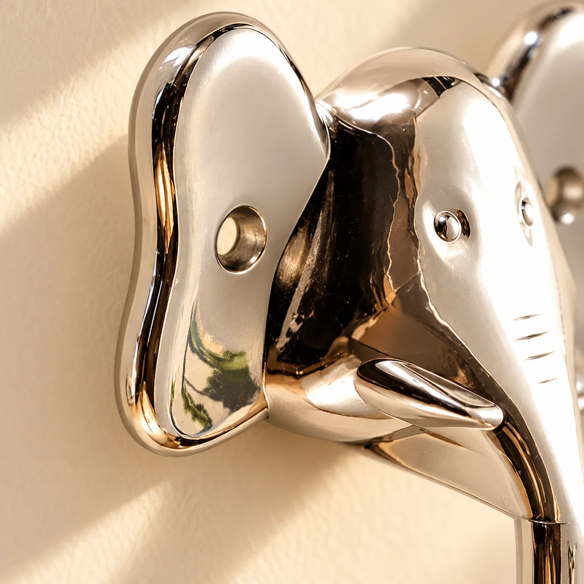 Gros plan de l'oreille, du trou de fixation et de la finition chromée de la patère éléphant