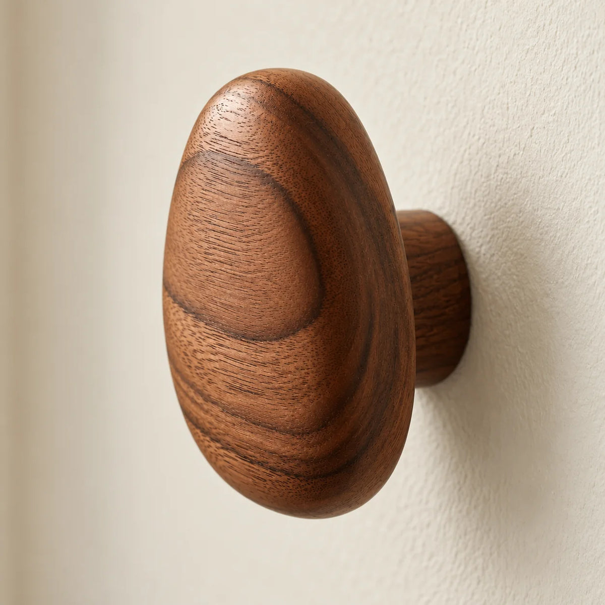 Détail du profil et du bois d'une patère ovale brun foncé fixée au mur