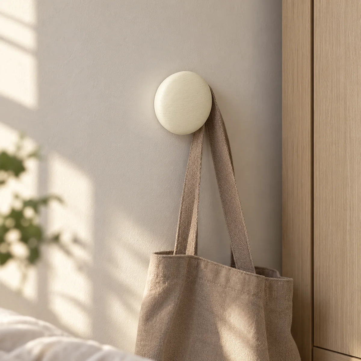 Patère ronde blanche portant un sac dans une chambre