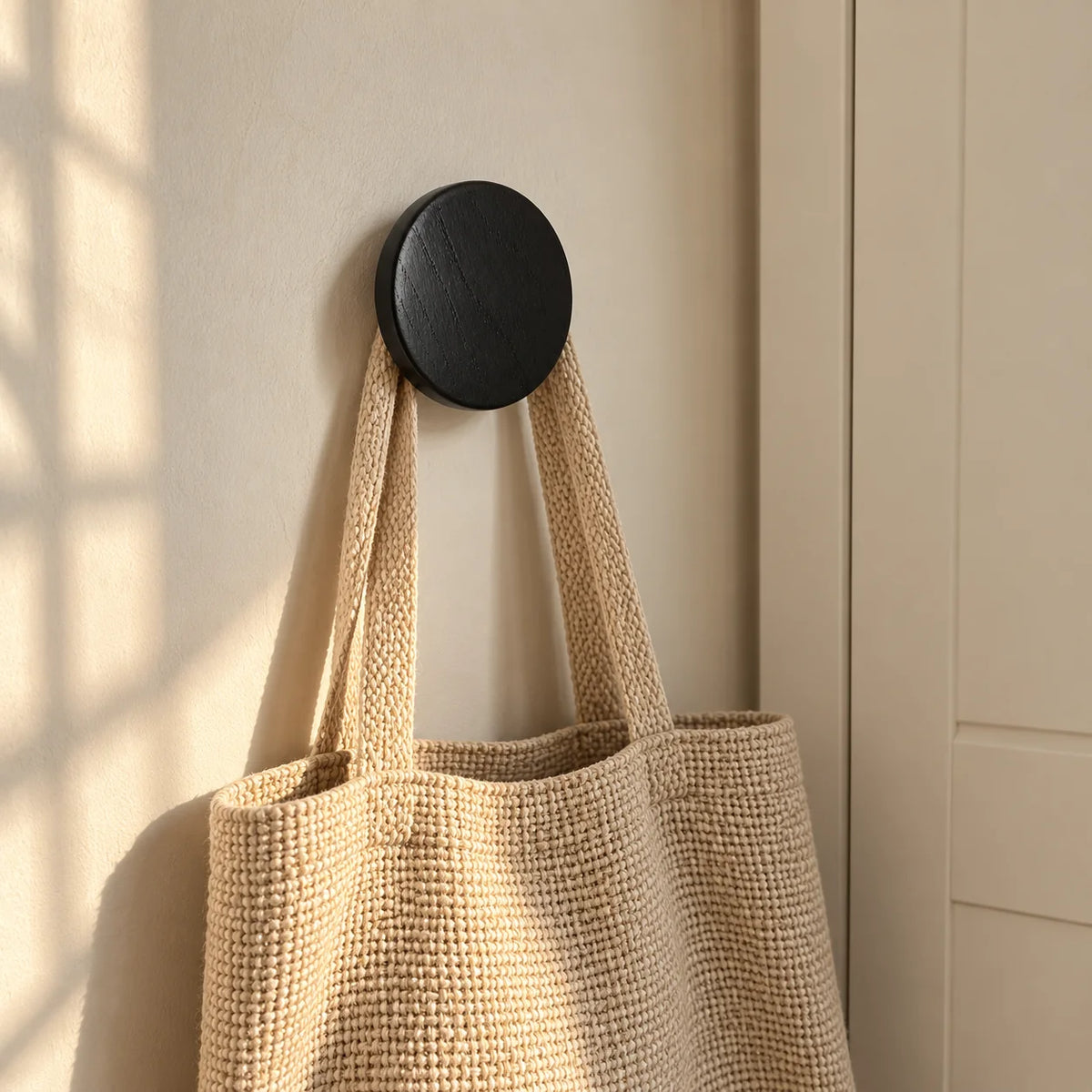 Patère ronde noire portant un sac dans une chambre