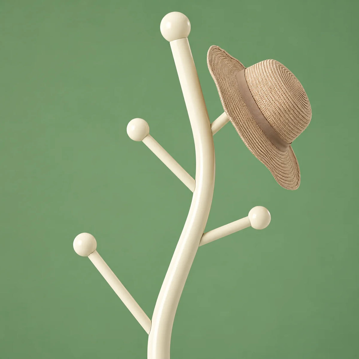 Détail du sommet courbe en métal blanc crème et de ses crochets à boules avec chapeau de paille sur fond vert sauge
