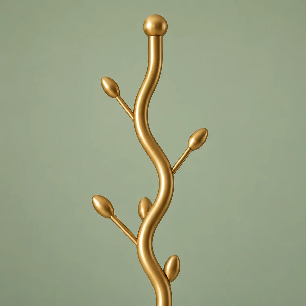 Détail du sommet doré à boule et des branches incurvées à embouts allongés sur fond vert sauge