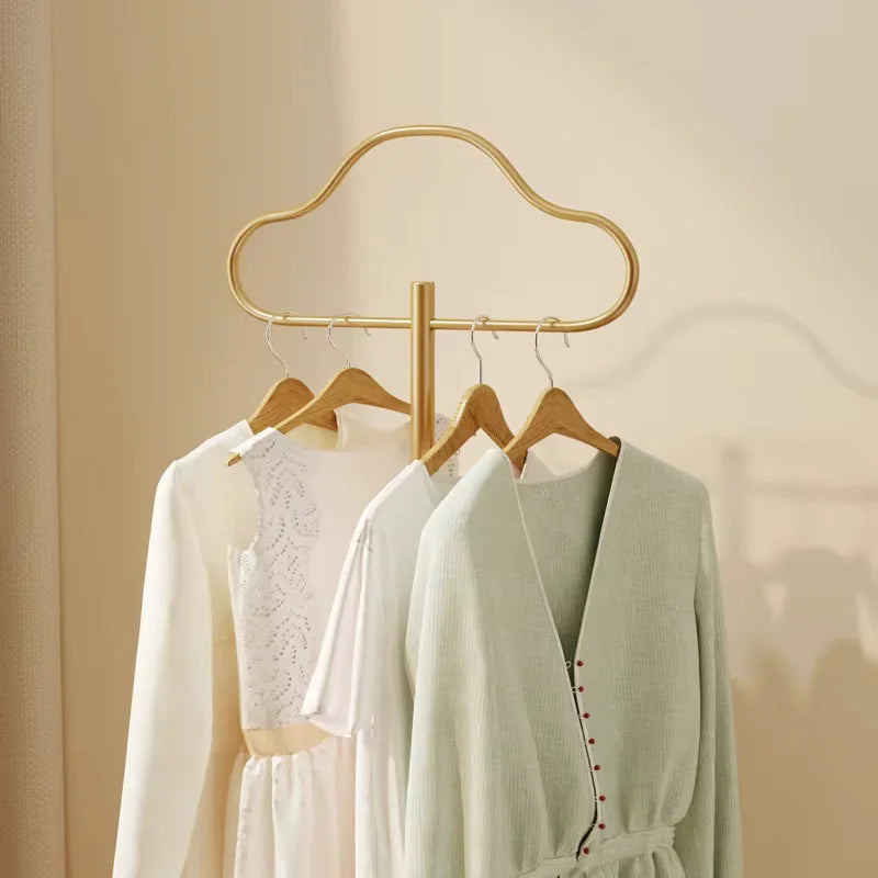 Gros plan de la barre dorée en forme de nuage du porte-manteau portant des vêtements