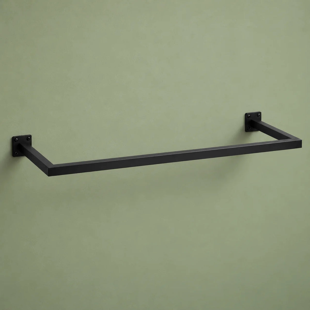 Barre porte-manteau murale noire vide, fixée sur un mur vert sauge