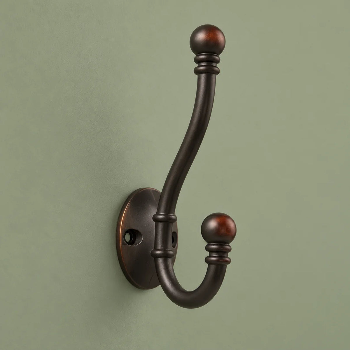 Vue complète de la patère double bronze foncé sur fond vert sauge