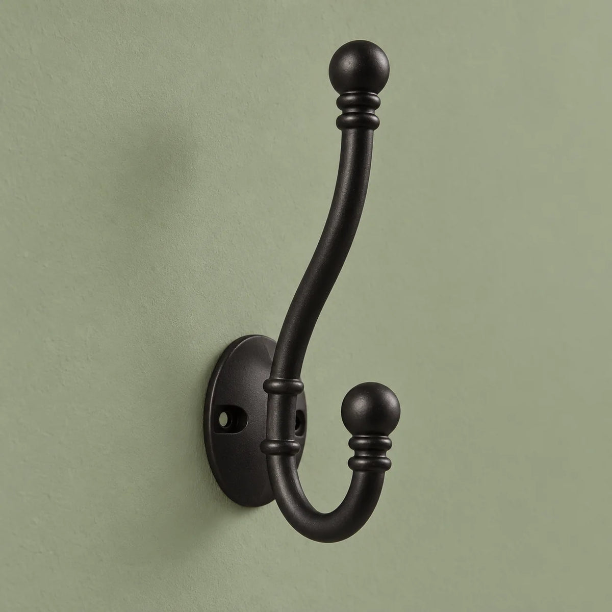 Vue complète de la patère double noire à embouts ronds sur fond vert sauge
