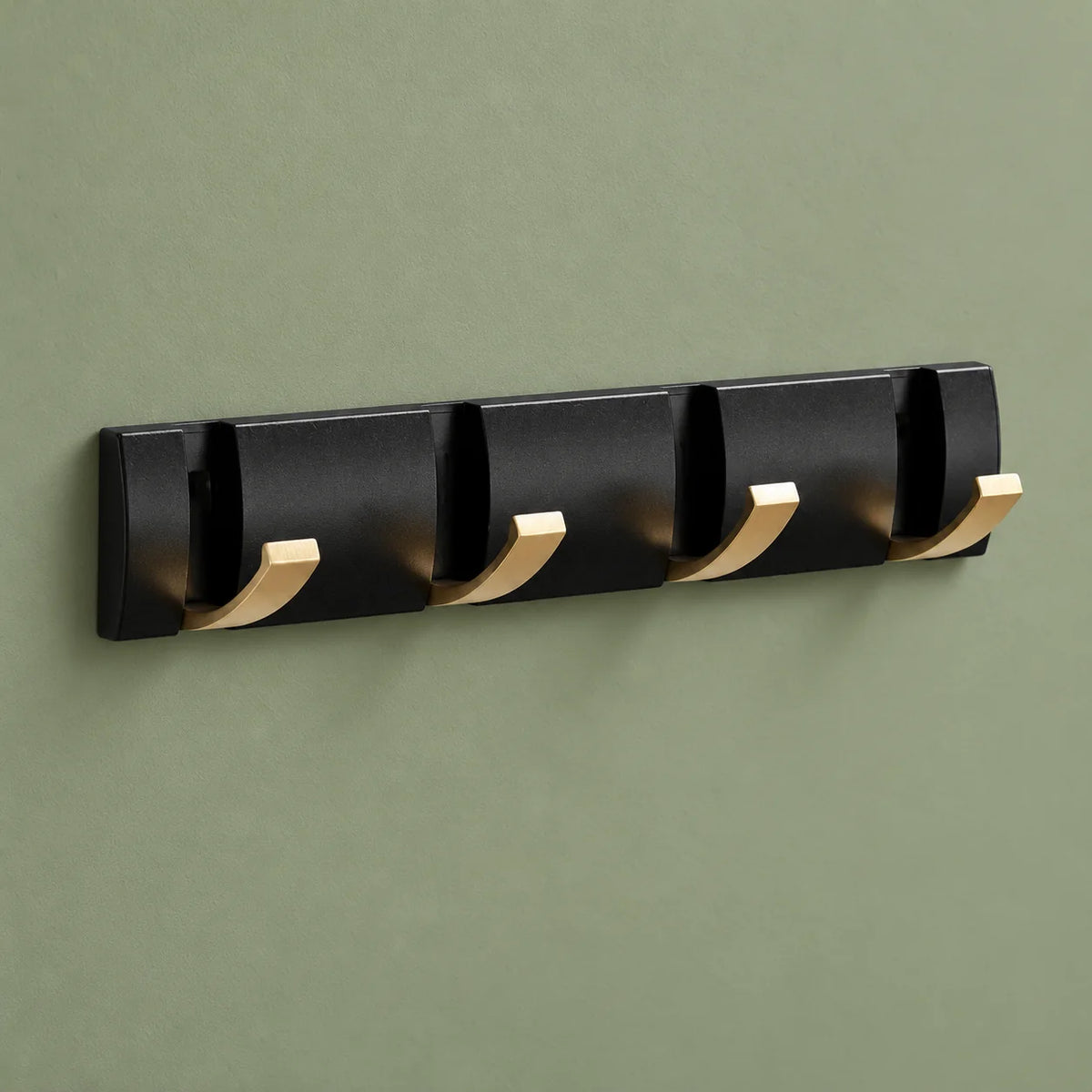 Vue entière du petit porte-manteau noir et doré à quatre crochets sur fond vert sauge