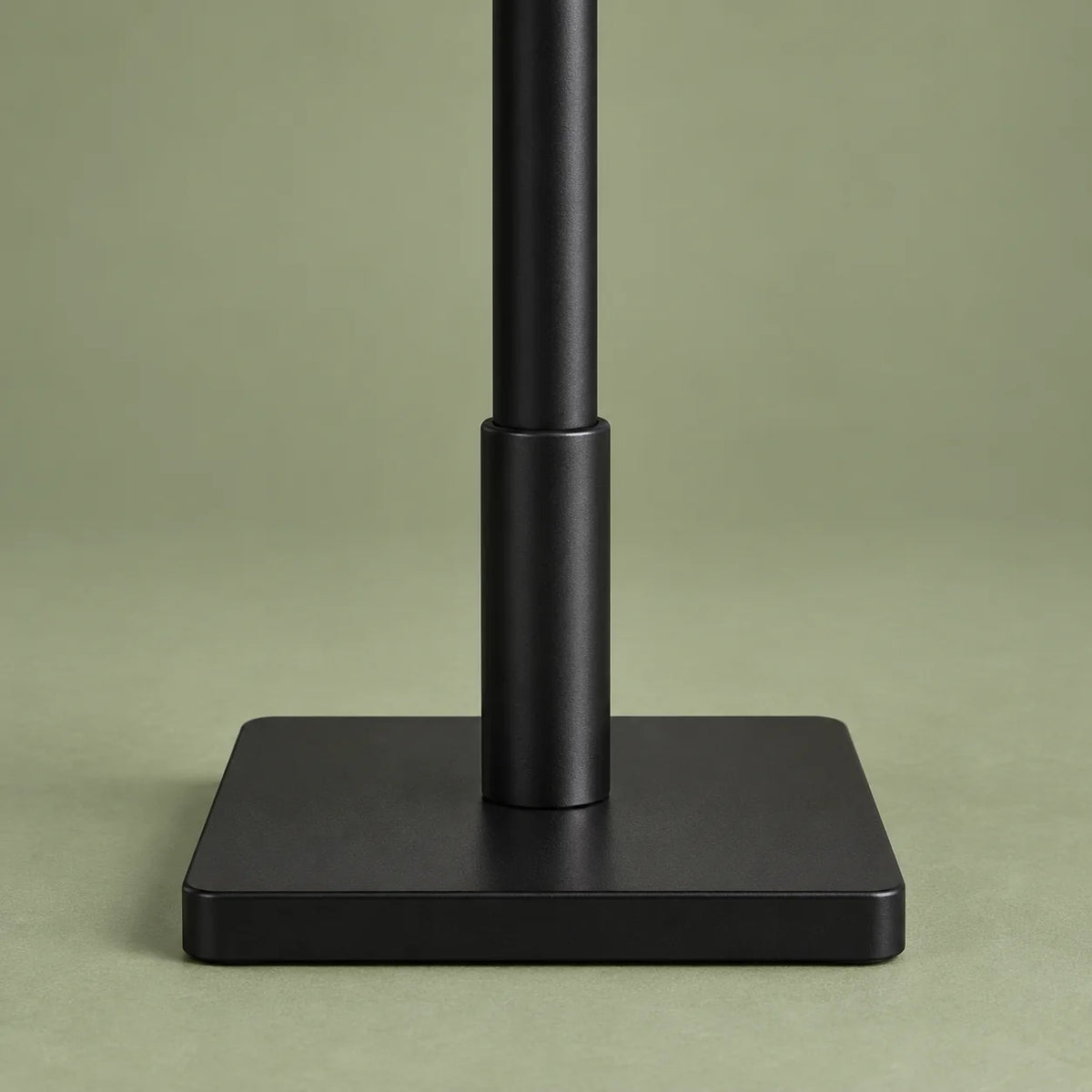 Détail de la base carrée noire du porte-manteau arbre sur fond vert sauge