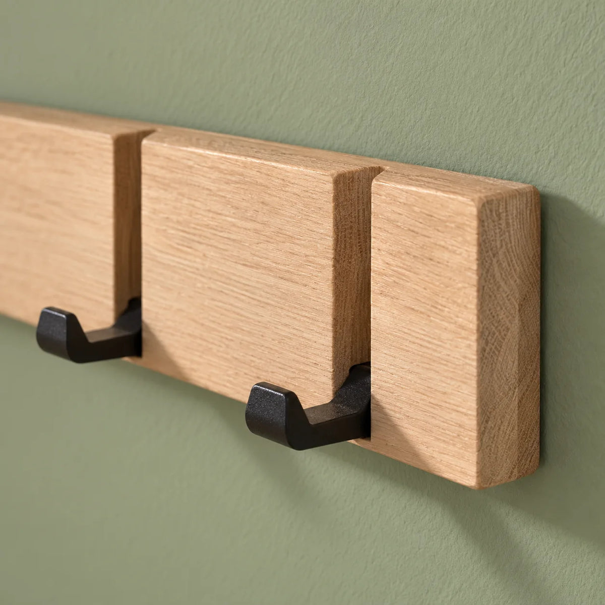 Détail de l’extrémité droite en bois beige et des crochets noirs rabattables