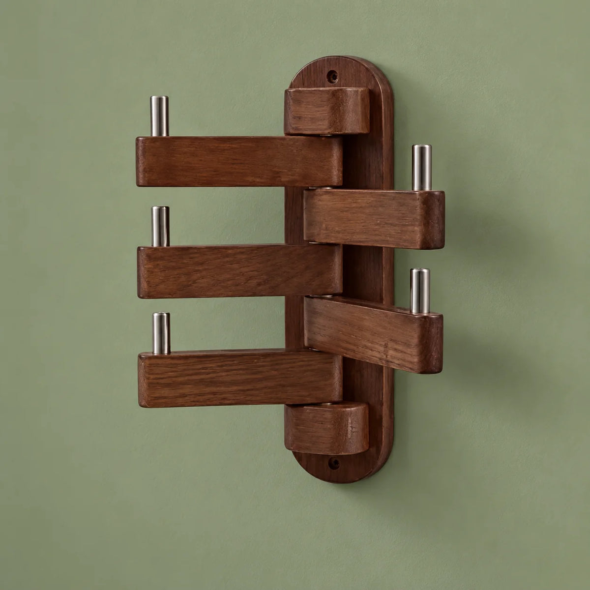 Porte-manteau mural pivotant en bois marron foncé, cinq bras déployés sur fond vert sauge