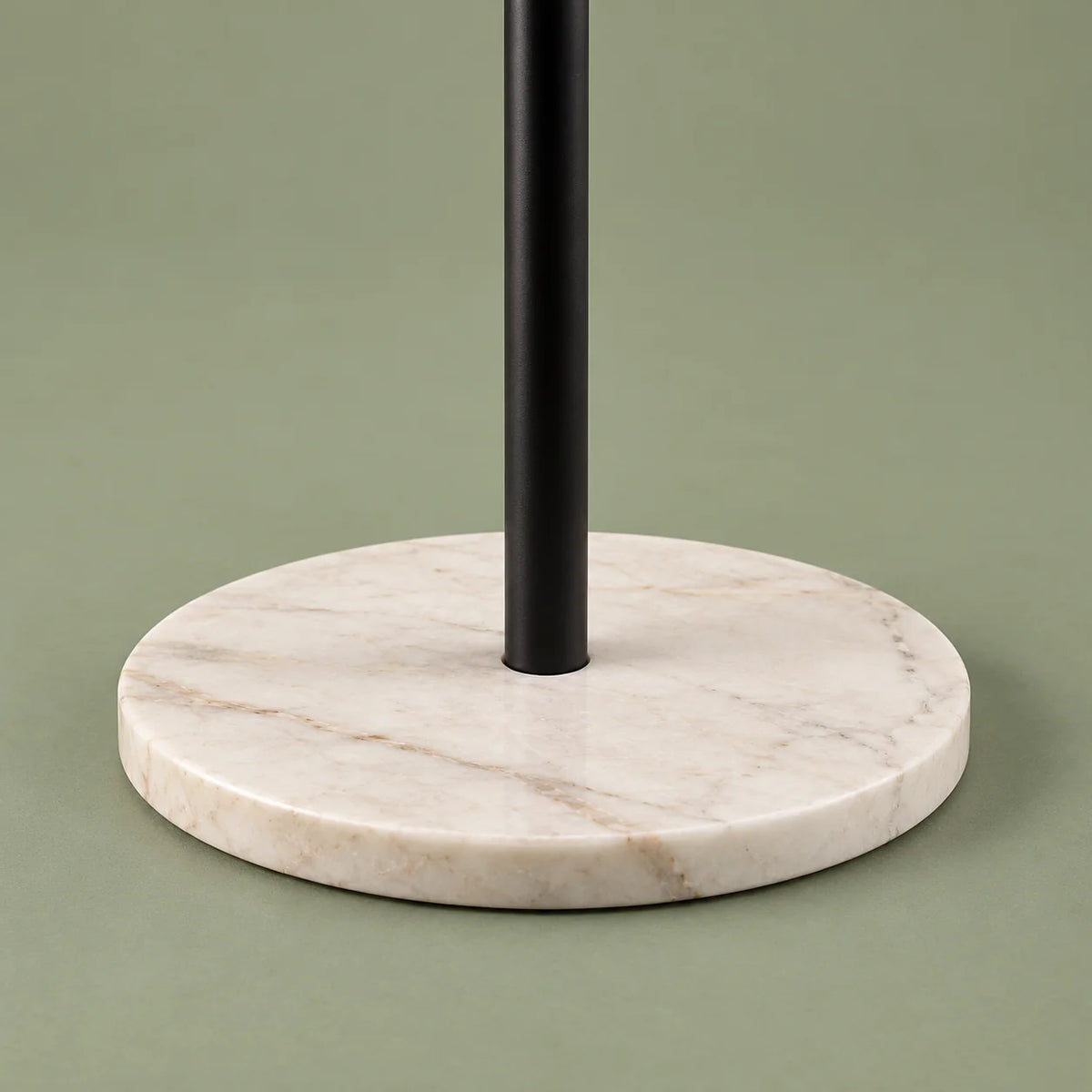Détail de la base ronde blanche veinée du porte-manteau sur fond vert sauge
