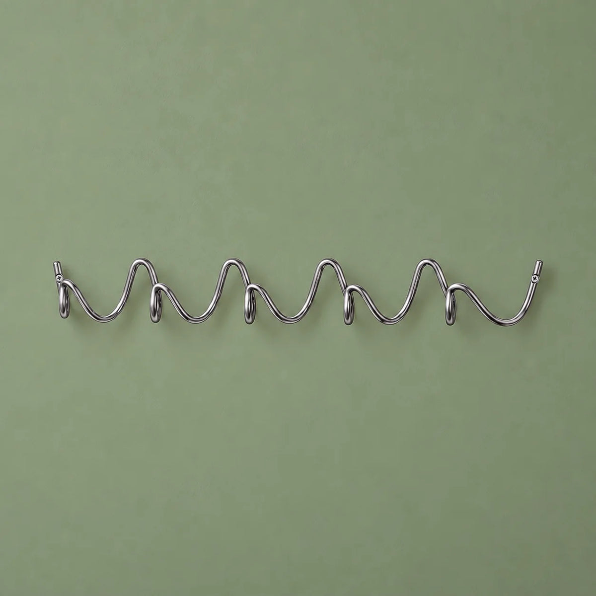 Porte-manteau mural Vrille chrome complet, de face sur fond vert sauge
