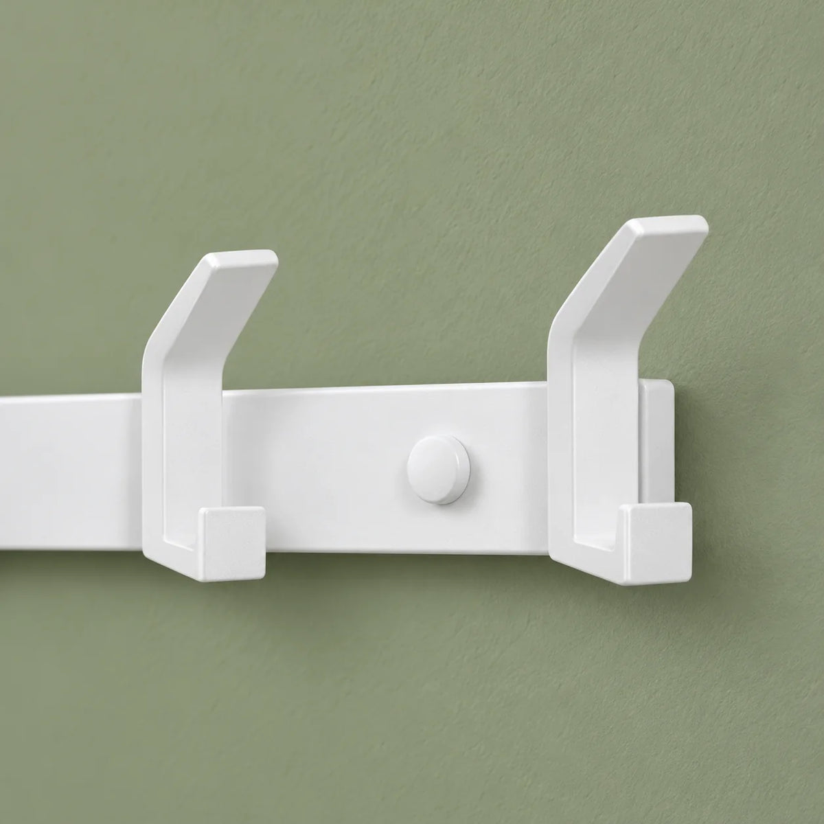 Détail des crochets blancs de droite du grand porte-manteau sur fond vert