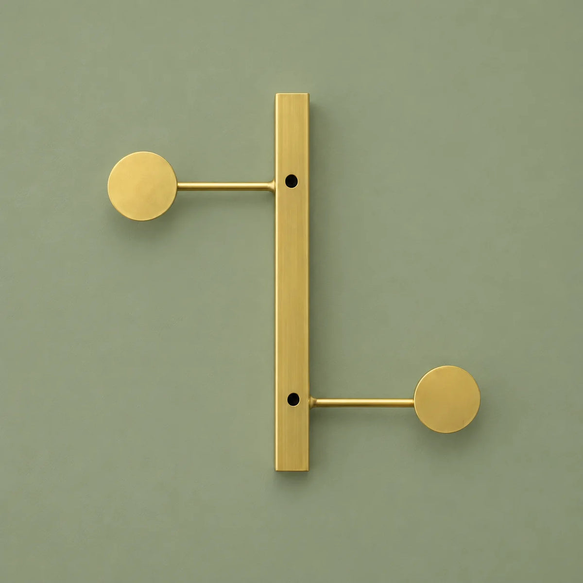 Vue complète du porte-manteau mural doré à deux crochets sur fond vert sauge
